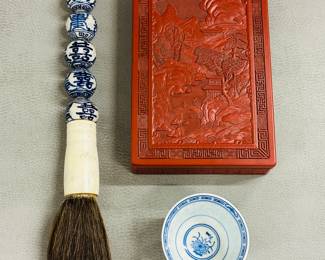 A Chinese calligraphy brush with a handle featuring hand-painted blue and white porcelain beads, a rectangular finely carved red lacquer cinnabar lidded box, and a Chinese underglaze blue and white porcelain tea cup 