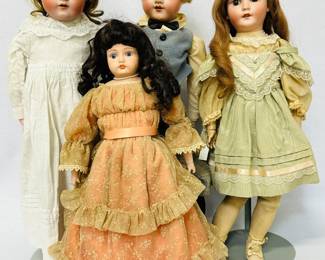 Antique and vintage dolls including a 23" bisque head doll, long curling brown wig, wearing a cream and green ribbon trimmed dress, stockings, and shoes; and a blue-eyed bisque head doll that's 19-3/4" tall, wearing a necklace and a lovely gathered dress with tiers of lace on the skirt and lace at the sleeve cuffs.