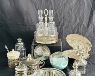 A selection of vintage and antique silver plated items including two antique Art Nouveau sterling silver overlay perfume bottles, a vintage silver plate clam shell hinged dish, a silverplate and glass cruet set, a porcelain sugar or condiment dish in silver plated holder with a figural spoon, and a small vintage cut glass or crystal bowl in an openwork silver-plate holder