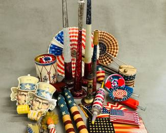 A collection of vintage patriotic American themed toys and noisemakers, many with the U.S. flag decoration, inncluding a pair of vintage-style Uncle Sam party blowouts or noisemakers, decorative tin litho toy drums, vintage tin sparkling spinner toys, and paper fans
