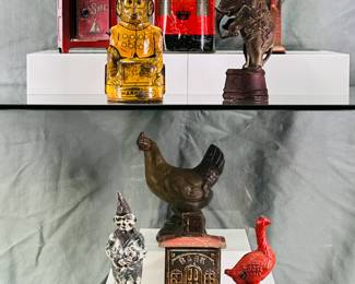 A collection of antique and vintage piggy banks, primarily mechanical and still banks including a post office box, a lithographed tin monkey (likely by J Chein), antique cast iron elephant still bank, made by the A.C. Williams Company or Arcade; a Red Goose Shoes advertising cast iron coin bank, a red cast iron bison or buffalo coin bank,  an antique or vintage A.C. Williams cast iron clown still bank. 
