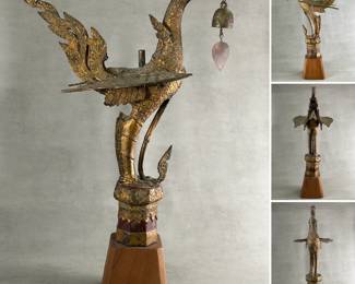 A Thai gilt bronze temple bird, known as a Hong or Hamsa, holding a small wind bell in its mouth, and mounted on a wooden base.  Approximately 2 feet tall including base.