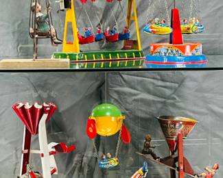 Vintage toys with a carnival theme including an A. Rowley Rhythm "Klippity Klop" cowboy sand tin toy, a vintage tin litho globe carousel with rocket riders, Josef Wagner Western Germany; vintage wind up tin boat or gondola swing ride, a  vintage J. Chein tin litho wind-up handstand clown toy, and a 1950s vintage vintage J. Chein & Co. "Busy Mike" tin lithograph sand toy.
