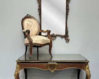 A Napoleon III Boulle Inlay Bureau de Plat, 3rd quarter of the 19th Century. Crafted in the style of Louis XV with cabriole legs adorned with female allegorical figures, the red tortoiseshell top meticulously inlaid with brass depicting Diana the Huntress riding her chariot amidst scrolls and floral details. A large single drawer with a shield at center, and with a custom carved glass top. A Napoleon III Boulle Inlay Arm Chair, 3rd quarter of the 19th Century, and a gorgeous and large antique carved giltwood mirror with&nbsp;ornate, hand-carved frame with C-scrolls, rocaille, and floral motifs 64" H x 34" W