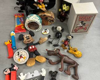 Mickey Mouse toys and collectibles including a vintage Mickey Mouse on Skis bisque porcelain figurine, a vintage Walt Disney Mickey Mouse flat rag doll plush, a Schylling or Young Epoch Mickey Mouse wind-up figure from the "Mickey Mouse and friends Retro Toy Collection," PEZ dispensers with Donald Duck, Goofy, Mickey Mouse; a vintage Pluto figurine, a Mickey Mouse Pocket Watch 
