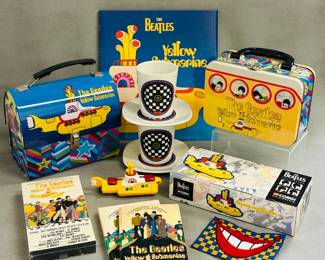 A collection of vintage The Beatles Yellow Submarine memorabilia including The Beatles Yellow Submarine dome tin tote / lunchbox, a The Beatles Yellow Submarine videotape, paperback books, and a Corgi The Beatles Yellow Submarine model kit