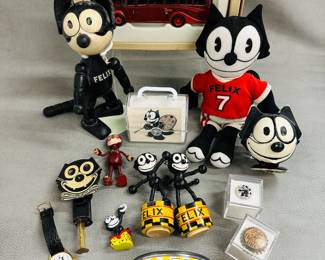 Felix The Cat toys and collectibles including a Felix Cat Food bank, Felix the Cat wooden push-up puppet toys, a Felix the cat lithographed metal sparkler toy, a Felix the Cat plush toy wearing a red jersey with number 7 and the name Felix on the front,  a vintage Felix Orange Dry soda bottle cap, and more