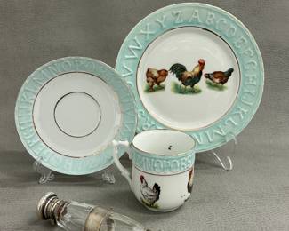 Another view of the Antique 19th century German porcelain child's "Alphabet" plate, cup, and saucer, the cup and plate decorated with chickens; stamped Germany on the base. Shown with antique Victorian double-ended scent bottle, made of cut glass with silver mounts, the caps engraved with "M" and "J".