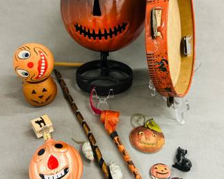 Vintage Halloween decorations and toys including a vintage paper Halloween party noisemaker, Jack O' Lantern metal sculpture, a tambourine decorated with black cats and moon face, a painted glass Halloween ornament, and carved pumpkin face buttons