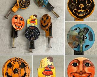  vintage tin lithographed noisemakers, "ratchet noisemakers," used for celebrations like Halloween or parties. They feature various designs, including a black cat, a moon face, a girl, and a jack-o'-lantern.