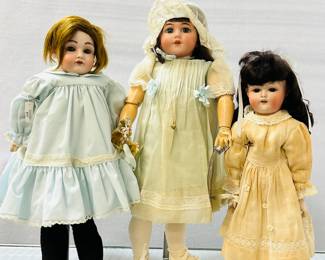Antique dolls in dresses, some wearing bonnets, stockings, and shoes