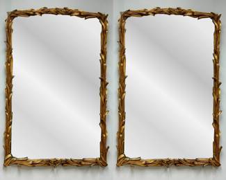 An elegant pair of vintage gilded wood mirrors with graceful foliate design frames. 42" H x 27" W.