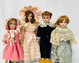 Antique dolls in fabulous clothing including a 16-inch JD Kestner JDK 174 bisque head doll wearing a blue velvet and lace suit, an Armand Marseille doll carrying a small doll in right hand, marked on back of model with "3200 AM 3/0 DEP made in Germany" and standing 15" tall, and a 15-inch bisque head doll in beautiful pink lacy dress and hat.