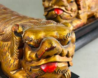 Closeup view of the pair of carved and lacquered gilt wood fo dogs or lions, on black lacquered wooden bases; made in China