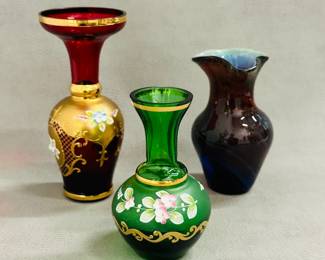 Art glass: A vintage Bohemian ruby red glass bud vase with hand-painted gold gilt and floral enamel details, a vintage Bohemian or Czech emerald green glass bud vase with hand-painted floral enamel and gold accents, and a hand-blown art glass bud vase with ruffled flared rim showing cased glass