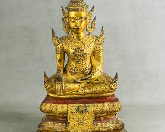 A Thai gilt bronze Buddha statue – the Buddha is depicted wearing lavish, ornate courtly robes with jewelry and a tall, winged crown, and is seated in the bhumisparsa mudra (earth-touching gesture) on a three-tiered base painted with red and black lacquer. With purchase card from Marshall Field & Company dating it to 18th Century.