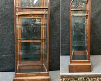 An antique wood and glass country store display or curio cabinet, with label reading Joseph Knittel Showcase Co. Show Cases, Drug Store, Bank, Office Fixtures Quincy, ILL.
