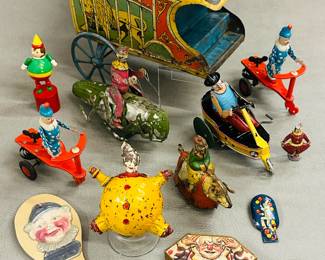 Vintage and antique circus-themed toys, several are tin lithograph including an antique "Clown Riding Grasshopper" wind up toy made by the German toy company Hans Eberl, a vintage tin Paya Clown on Tricycle (or "Carrito Ramper") wind up toy, a German tin windup toy of clown riding a pig