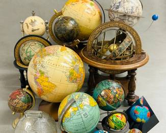A collection of vintage and antique globes featuring globes of various sizes, styles, and materials, including a glass globe, tin globe bank, and an armillary sphere