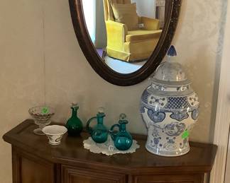 Cabinet in foyer with blue and white ginger jar and hand blown bottles.