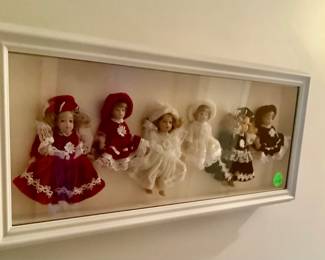 A shadow box frame with dolls.