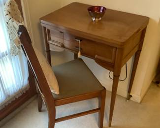 The Singer sewing machine in cabinet with chair.