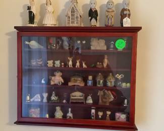 The wall hanging cabinet with a lot of different collectible items. Has glass front.