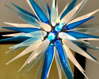 Hand-Blown Murano Glass Chandelier This exceptional hand-blown Murano glass chandelier exemplifies the artistry and tradition of Italian glassmaking. The fixture is composed of 61 individually crafted glass elements, each meticulously formed by skilled Murano artisans, creating subtle variations that make the chandelier truly one of a kind. Finished with brushed chrome hardware, the chandelier offers a refined, contemporary contrast to the organic beauty of the glass. When illuminated, the cascading elements create a luminous and sculptural presence, casting an elegant ambient glow. • Materials: Hand-blown Murano glass, brushed chrome hardware • Glass Elements: 61 • Dimensions: Approximately 39 in. W x 48 in. H A striking statement piece ideal for grand entryways, dining rooms, or double-height interiors, blending timeless craftsmanship with modern sophistication.