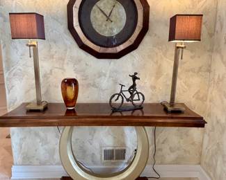 Console table 20" deep x 37" high x 66" long excellent condition. Pair of unique brushed gold lamps with fabric shades. Wall clock decor, art glass vase and metal sculpture
