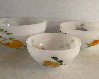  A vintage nesting set of Anchor Hocking Fire-King Gay Fad fruit-pattern milk glass mixing bowls, featuring hand-painted designs of peaches, grapes, and pears. 
