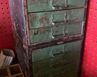 A small mid-century vintage industrial metal parts cabinet with distressed green paint patina and multiple drawers,  originally used for organizing hardware