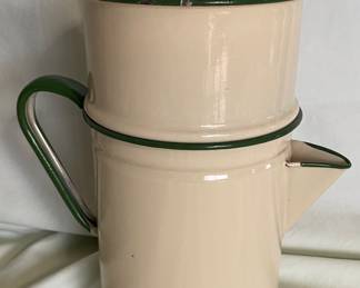 A vintage enamelware coffee percolator, featuring a cream-colored body with dark green trim.  The three-piece design includes a main pot, an inner basket/strainer for brewing, and a lid. 