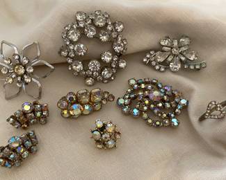 A collection of vintage rhinestone jewelry including brooches and clip-on earrings