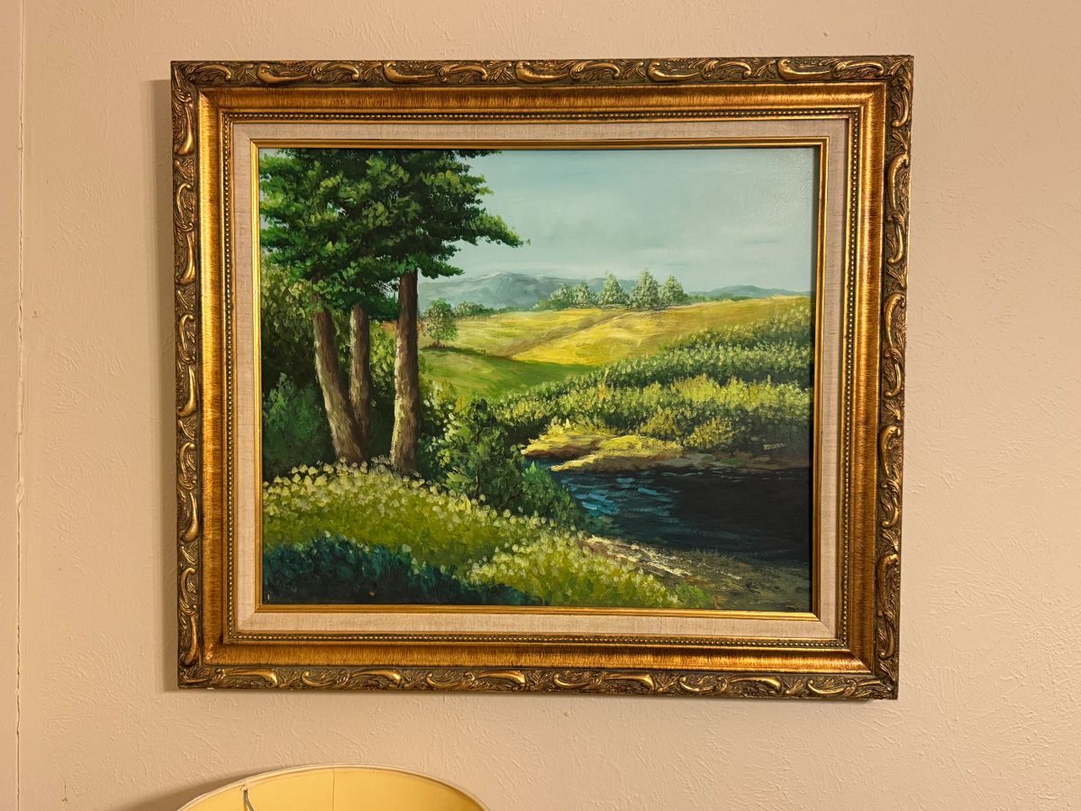 Serene landscape oil painting with lush trees and a winding river, framed in ornate gold.