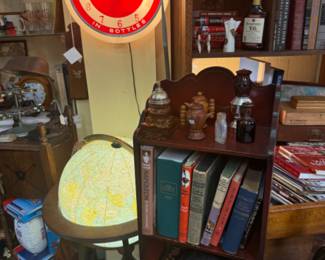 coca cola signage clock, small wooden bookshelf, vintage books, lighted globe
