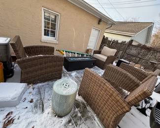 Four synthetic wicker chairs with seat and back cushions, two ceramic drum tables, linear gas firepit.