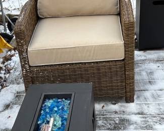 Synthetic wicker chair with cushions and linear gas firepit.