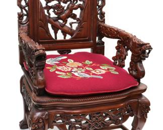 Pair of Wooden Dragon Chairs. These heavily carved wooden Asian chairs feature dragon heads on the end of the armrest. Also a bat, demons, and floral designs.