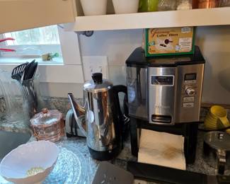 Coffee machine, BBQ utensils, Assorted knives, Glass creamer, Salt & Pepper shakers, Copper shaker, mugs, flour sifter, Vintage yellow measuring cups, Glass platters, Coffee Pot