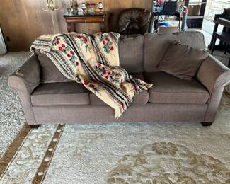 Brown sofa, large old Hollywood gold rug. Beautiful antique Afghan.