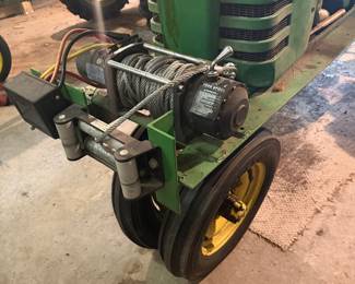  vintage John Deere tractor equipped with an aftermarket electric winch mounted on the front bumper. 
