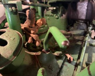 Vintage John Deere Model B tractor  A classic piece of agricultural machinery manufactured between 1935 and 1952.   John Deere B with a large exposed flywheel on the side. Equipped with a manual transmission and a power take-off (PTO) shaft for running implements. Gated gear shifter, heavy-duty metal pedals, and traditional mechanical controls with a distinctive two-cylinder design.