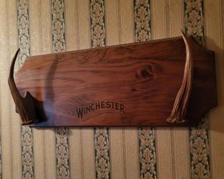 vintage-style wooden gun rack featuring antler mounts and the Winchester brand logo is designed as a decorative wall display for firearms. 