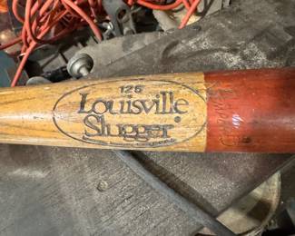 Vintage Louisville Slugger wooden baseball bat, Model 126, natural finish with red handle. Visible age wear consistent with use and storage. Approx. Dimensions: 34–35 inches long
