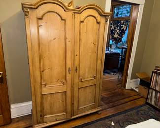 Antique-style pine armoire / wardrobe with paneled double doors, arched crown detail, and original hardware, Condition: Good, Price $300