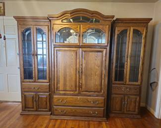 Large 3-Piece Solid Oak Entertainment Center / Wall Unit
Beautiful traditional oak entertainment center featuring a center cabinet with overhead display and two matching glass-door side cabinets. Includes multiple drawers and enclosed storage for media, décor, or collectibles.
Beveled glass panels, brass tone hardware, and classic arched crown detail. Extremely solid and heavy construction.
Measures approximately full wall width (bring help to move). Breaks down into three separate pieces for transport.
Excellent storage piece for a traditional home, office, or media room.