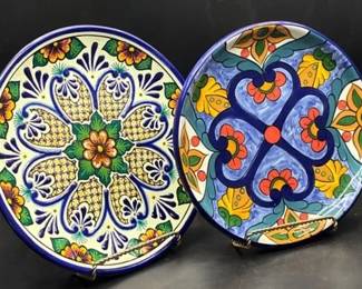Handpainted ceramic plates features a vibrant, multicolor floral pattern with a blue trim
