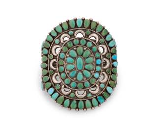181
A large Southwest Zuni Pueblo style silver and cluster set turquoise cuff bracelet
Early/mid-20th century
With etched marks and pictograms including an eagle, verso; further marked in ink: Old Pawn
A three-wire cuff with large set petit point turquoise openwork plaque and shoulders
6.75" total inner C x 3.5" H, with a 1" gap
96.2 grams gross
Estimate: $600 - $800