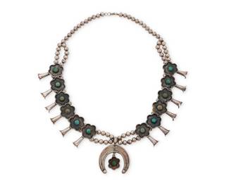 168
A Southwest silver and turquoise squash blossom necklace
Mid/late 20th century
Unmarked
A double-strand necklace with twelve floral blossoms, each with central set turquoise, all suspending a central five-wire naja with flower blossom dangle
27" L x 2.375" H
142.7 grams gross
Estimate: $700 - $900