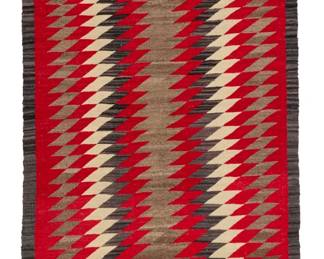 23
A large Navajo regional runner
Early 20th century, Diné
Woven in red, cream, natural grey, and dark brown wool, with alternating serrated vertical bands
124" L x 44" W
Estimate: $1,000 - $1,500